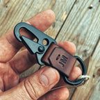 Lovecky Leather kožený přívěsek na klíče s černou karabinou – detail ručního šití a ražby monogramu.