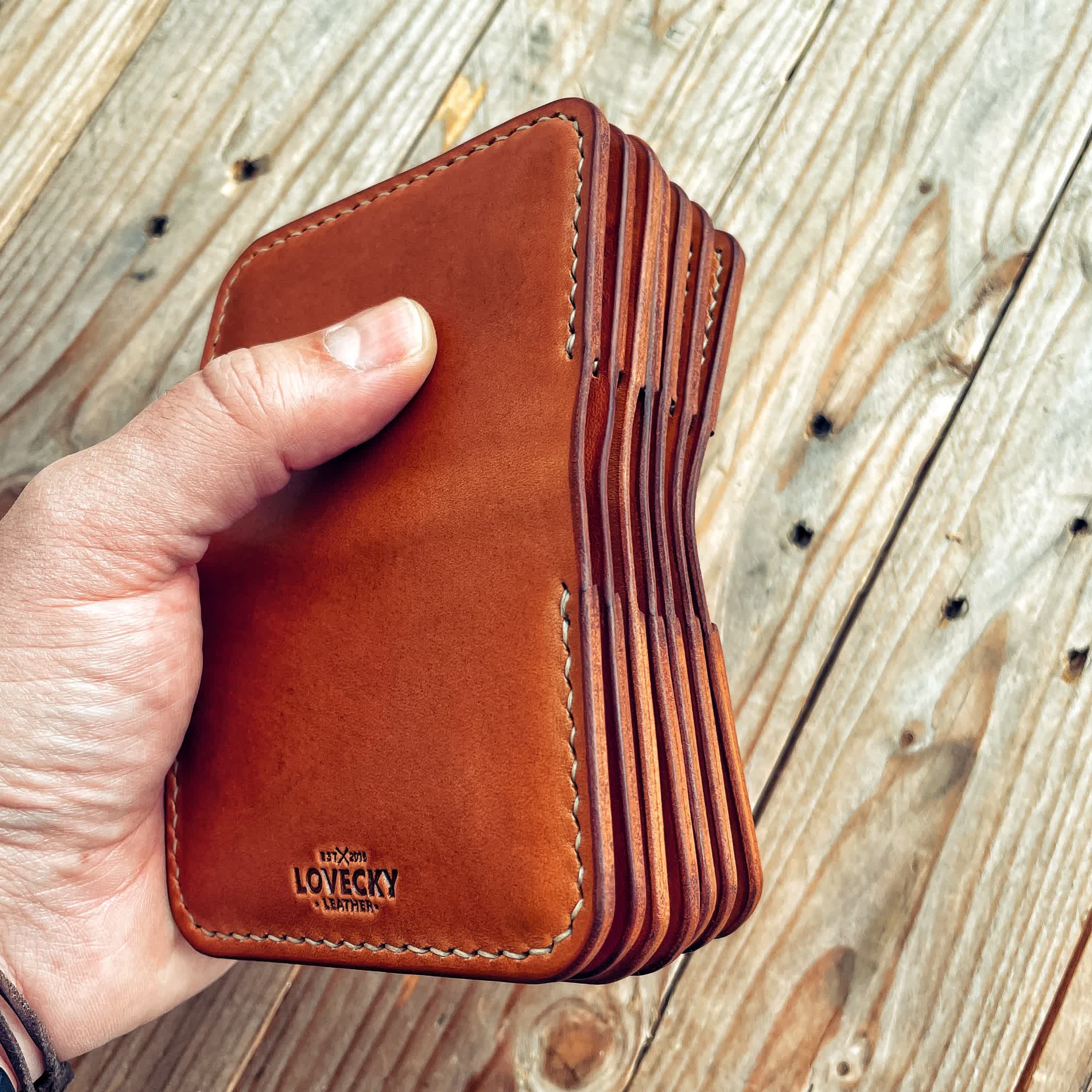 Lovecky Leather kožená EDC peněženka 59 v hnědé barvě, detail na pravou kůži, firemní logo, více kusů v ruce