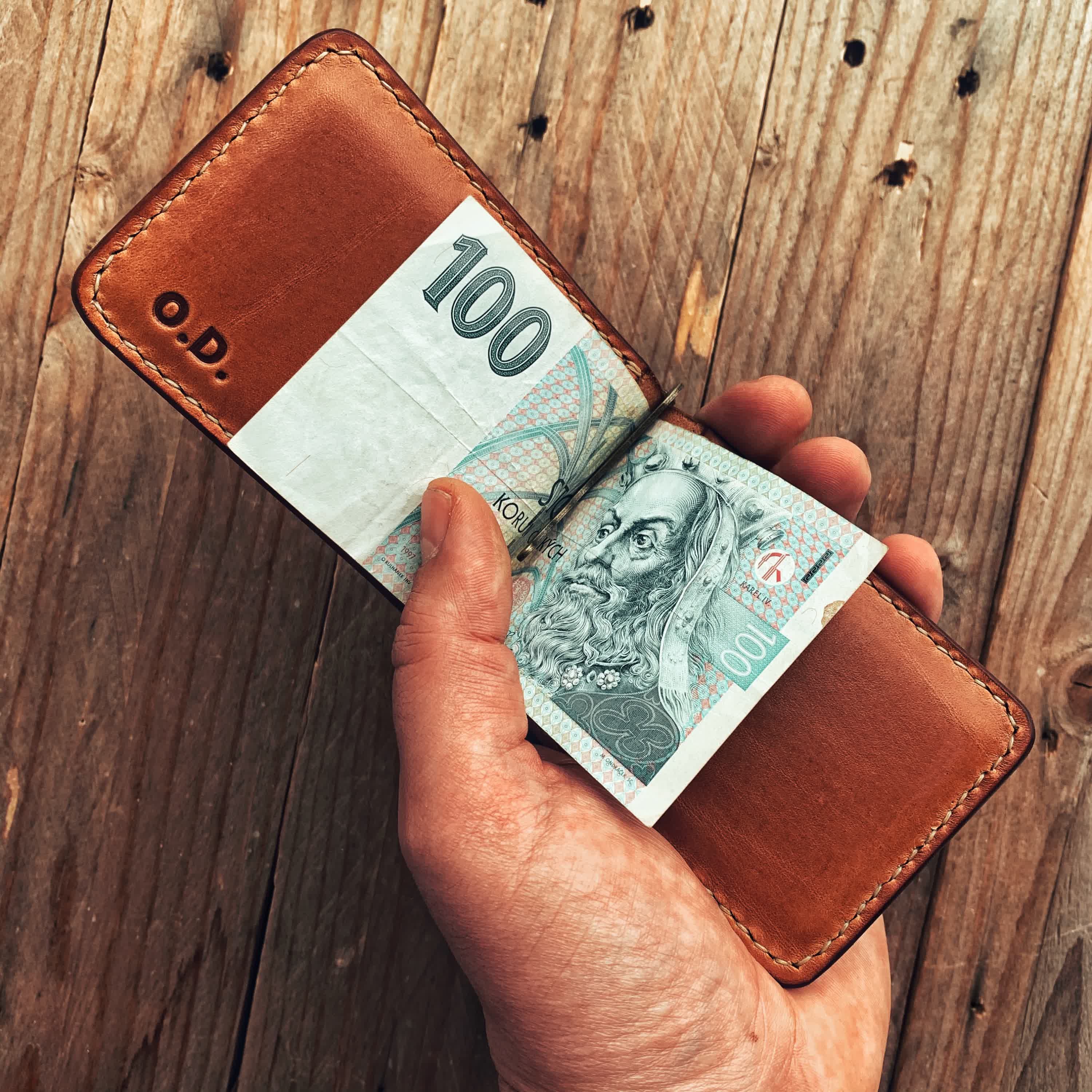Lovecky Leather kožená peněženka 62 dolarovka s výklopnou sponou na bankovky, s iniciály a vloženou stokorunou, držená v ruce