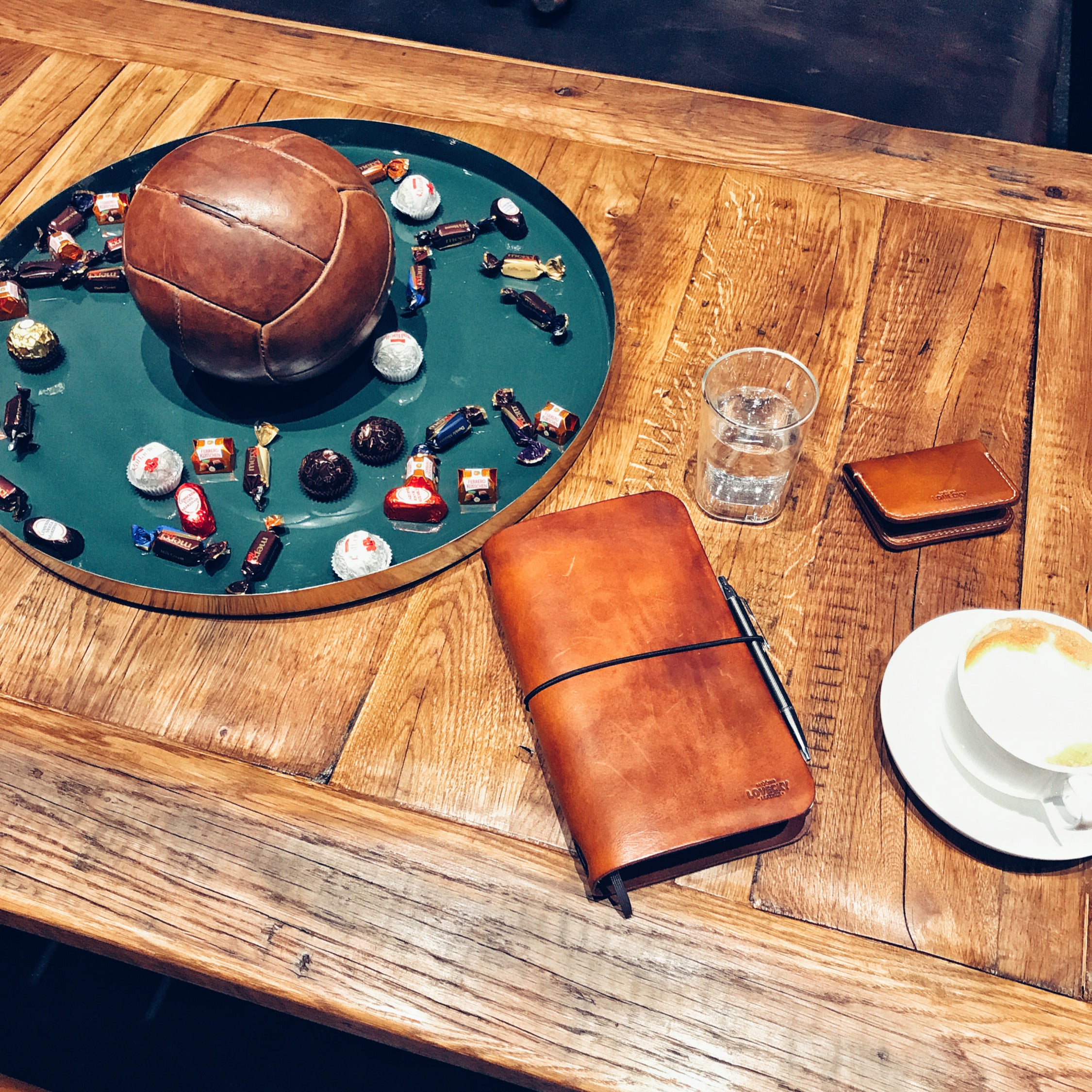 Lovecky Leather stylový kožený obal 77 na diář položený na stole, elegantní ruční výroba z hnědé kůže.