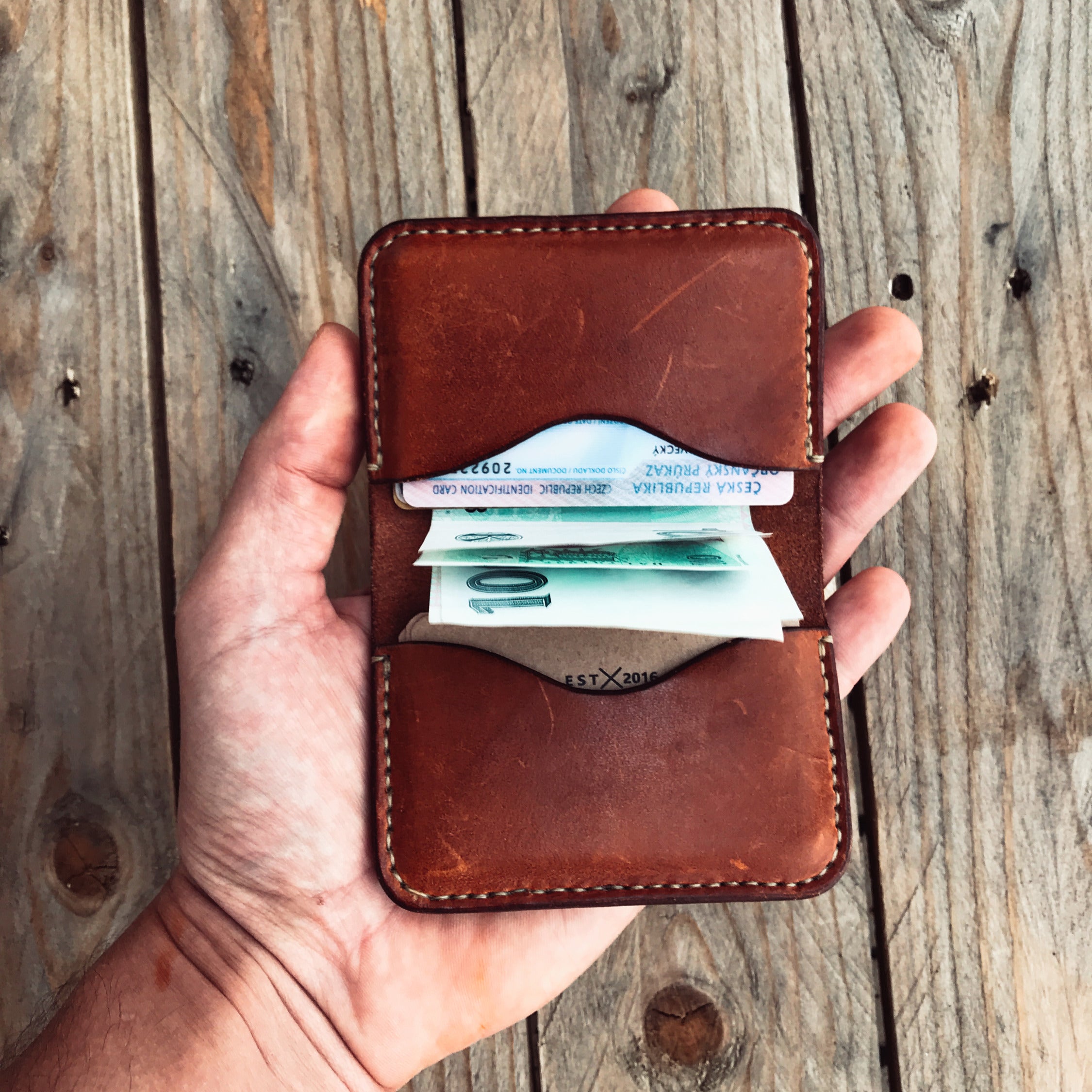 Světle hnědá peněženka 59 – otevřená v ruce, s bankovkami a doklady